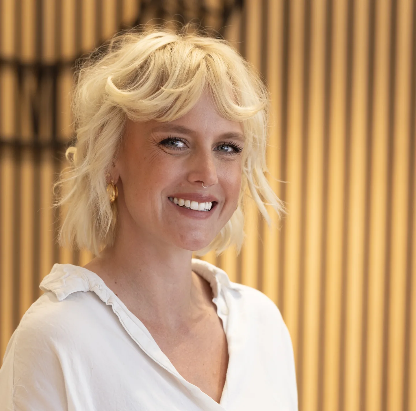 Portræt af Maja foran en trælamelvæg
