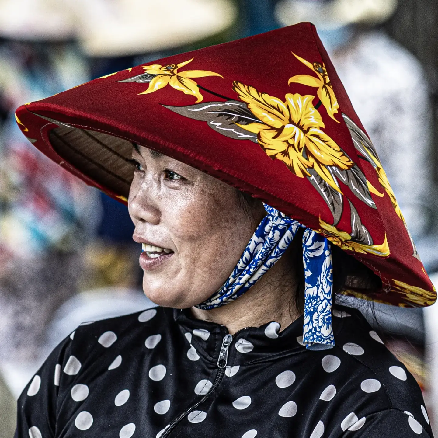 Kvinde med rød blomsterhat på et marked i Vietnam